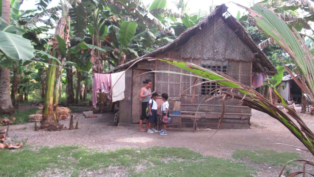 A family outside a traditional nipa hut