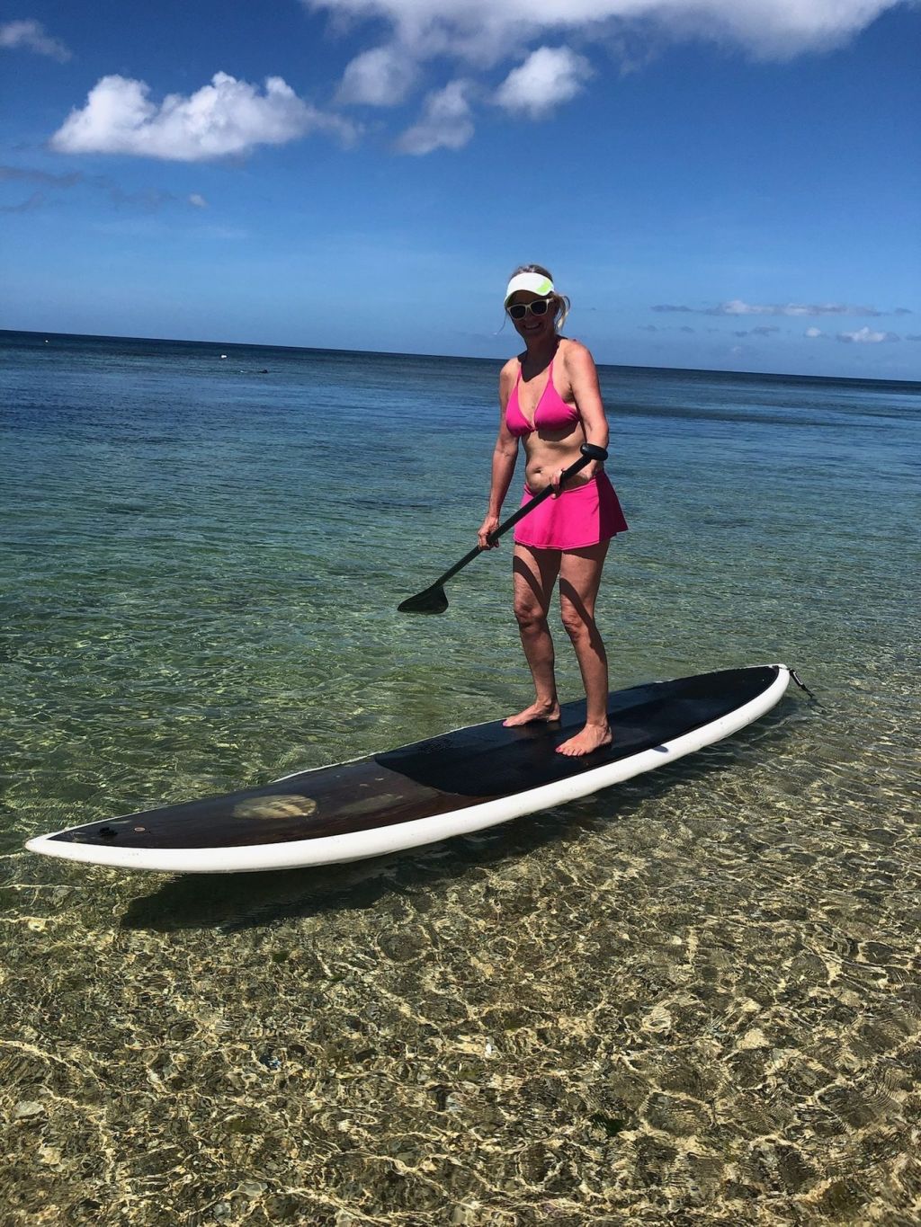 A guest on a stand-up paddle board over the clear shallows