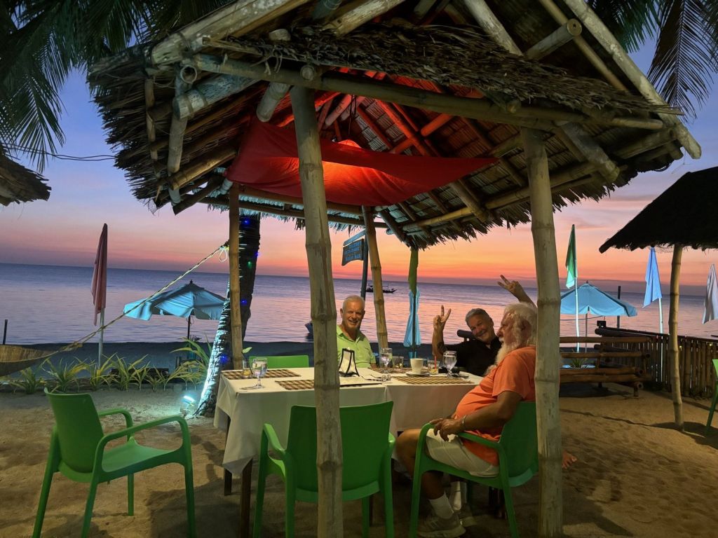 Guests dining on the beach at sunset