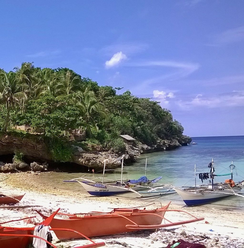 Banca boats in a cove below the cliffs