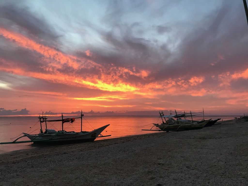 Boats on the shore under a red sky
