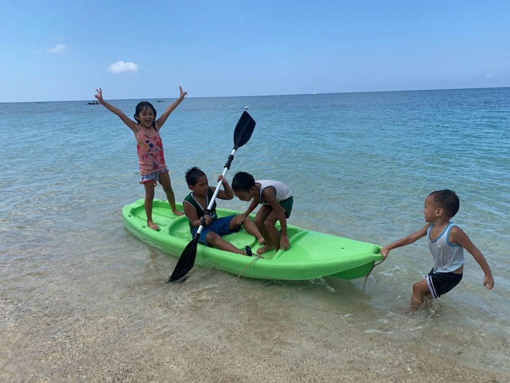Children playing with a kayak in the shallows