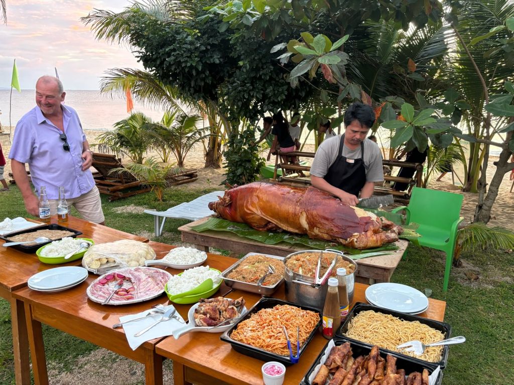 A party buffet on the lawn with a whole lechon and island dishes