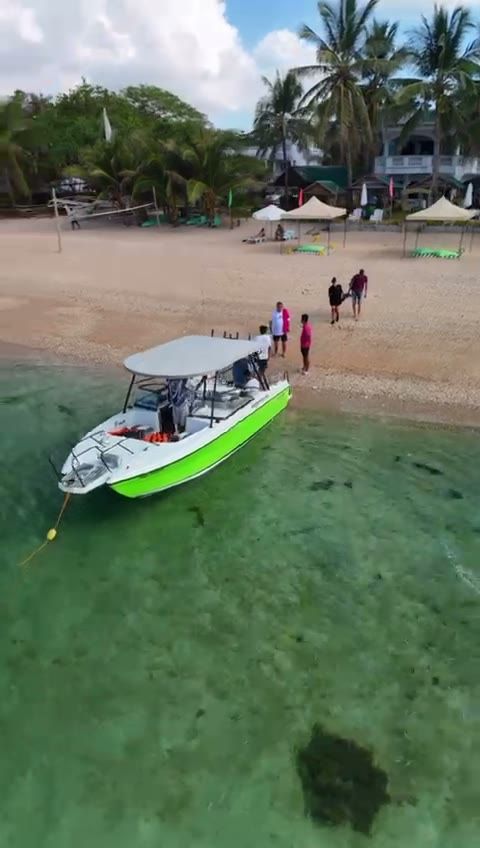 The beach in front of The Beach House from the air, with our speedboat at the shore and guests stepping off